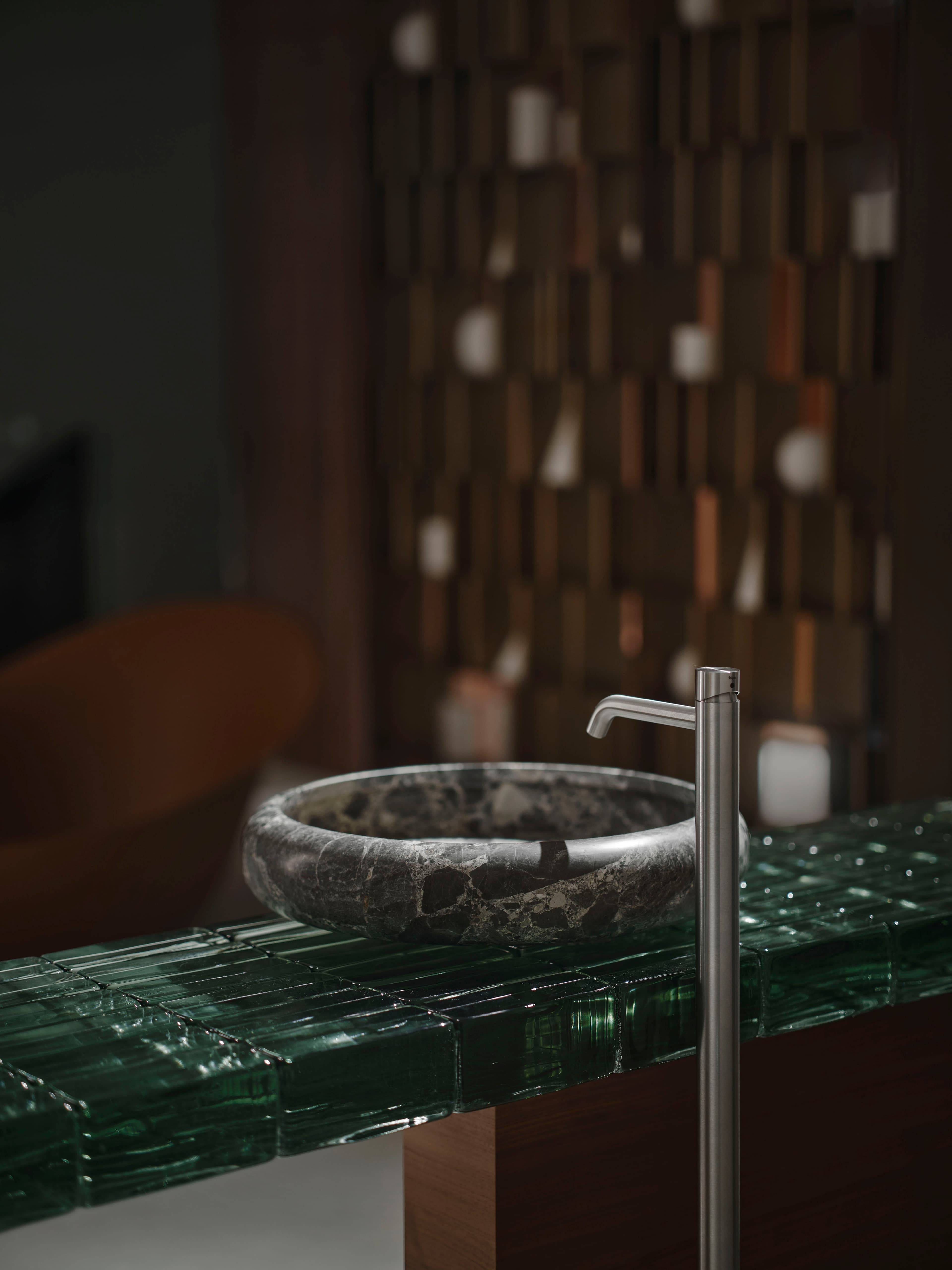 Lavabo in marmo su piano in vetro verde.